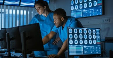 Two Medical Scientists / Neurologists, Talking and  Working on a Personal Computer in Modern Laboratory. Research Scientists Making New Discoveries in the fields of Neurophysiology, Science,  Neuropharmacology. Understanding Human Brain.